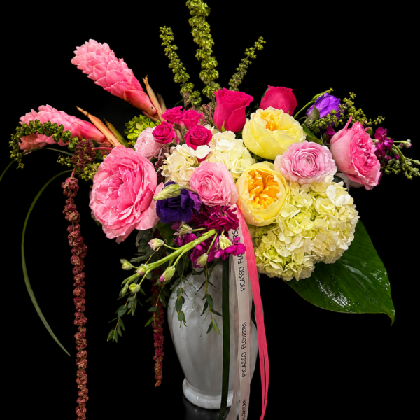 Luxury Mother’s Day flower arrangement in a white ceramic vase with pink roses, pink peonies, yellow garden roses, white hydrangeas, tropical pink blooms, greenery, and Picasso Flowers ribbon on a black background.